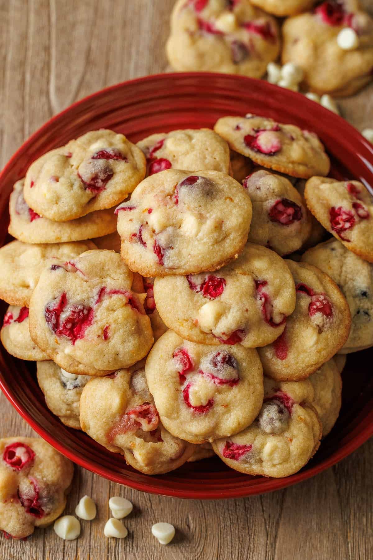 These White Chocolate Cranberry Cookies are soft and chewy festive treats with white chocolate chips and orange zest, a perfect blend of sweet and tart. White chocolate cranberry cookies stacked on a red platter