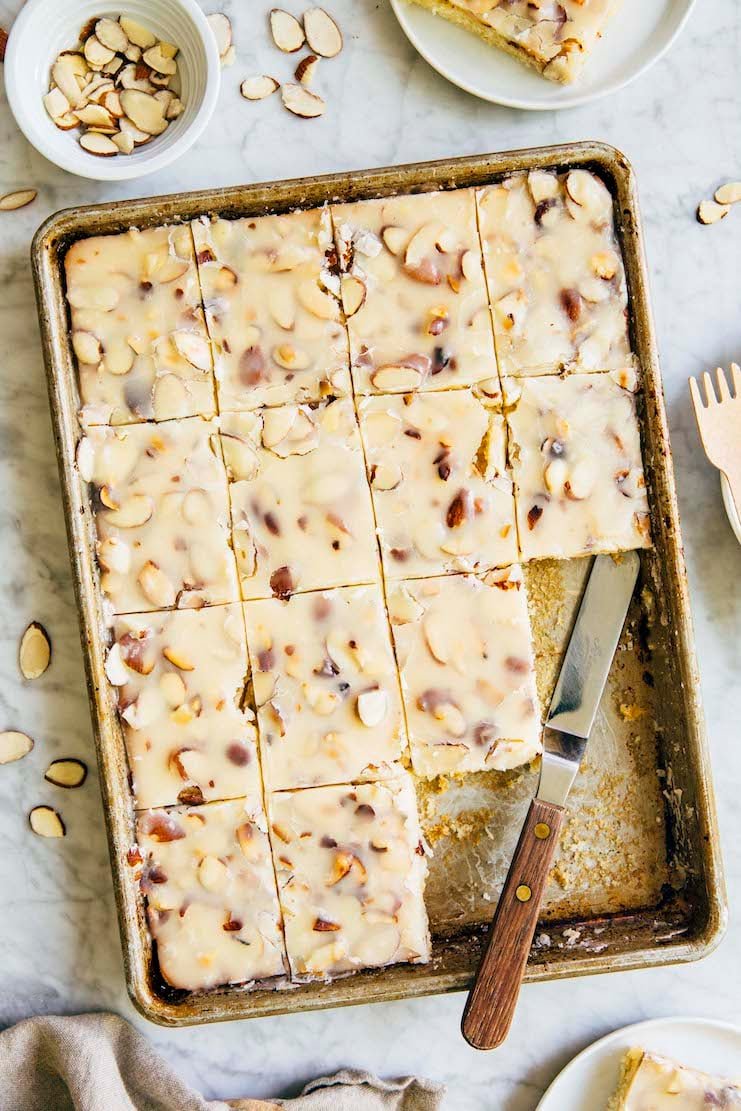 photo of a white texas sheet cake in a 9 x 13 inch pan on marble table with slices removed
