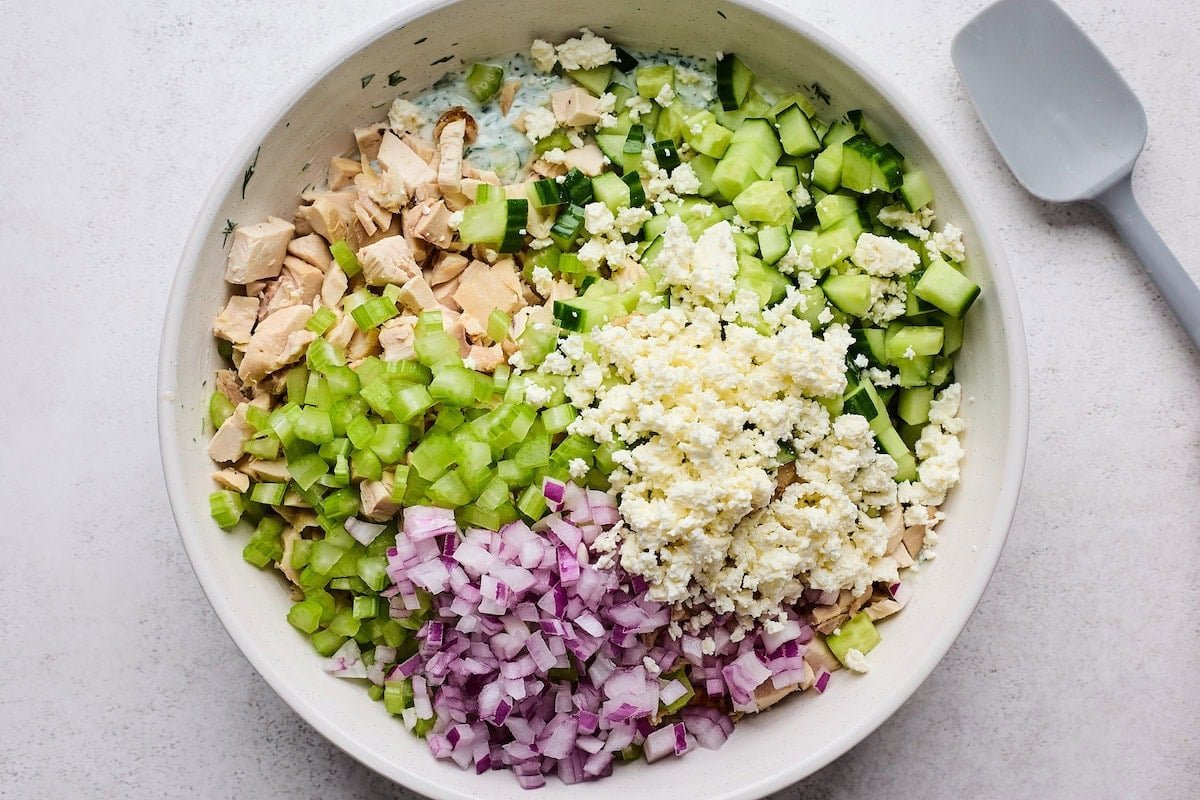 chicken, cucumber, feta cheese, red onion, and celery in bowl with tzatziki sauce to make tzatziki chicken salad.