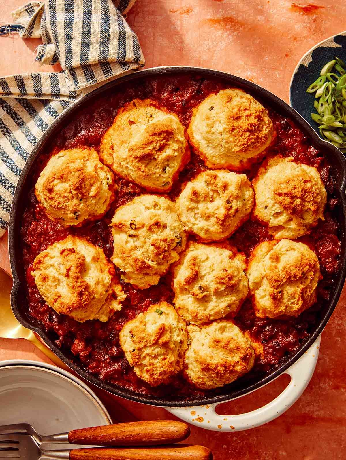 Chili cornbread casserole in a skillet with bowls next to it.