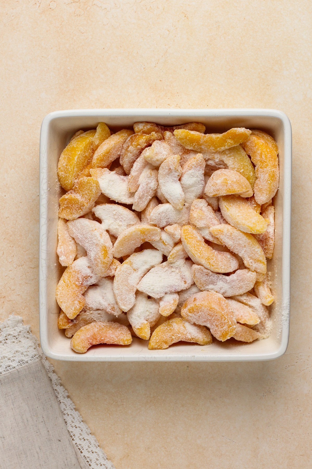 Peach crisp filling in a white baking dish.