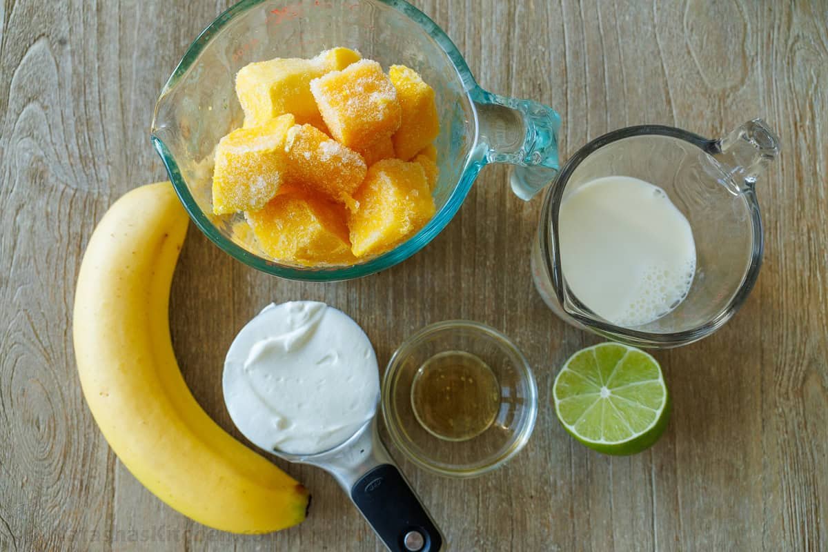 Easy Tropical Mango Smoothie recipe uses just 6 ingredients, like mango, lime, banana, and Greek yogurt, and takes under 5 minutes to make! ingredients for tropical slushie with frozen fruit, banana, greek yogurt, honey, milk and lime