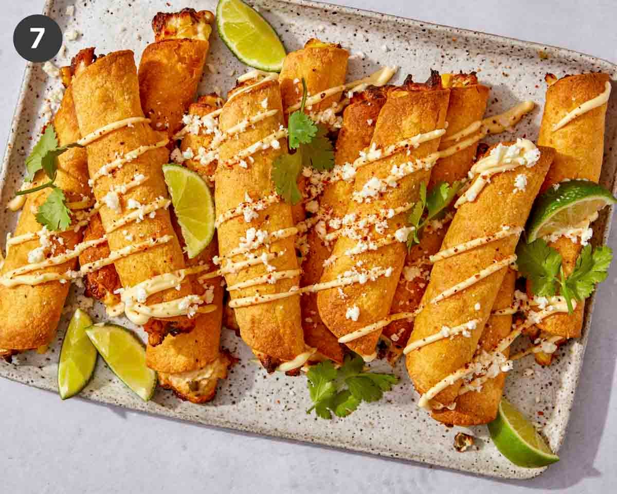 Air fryer taquitos on a platter with toppings.