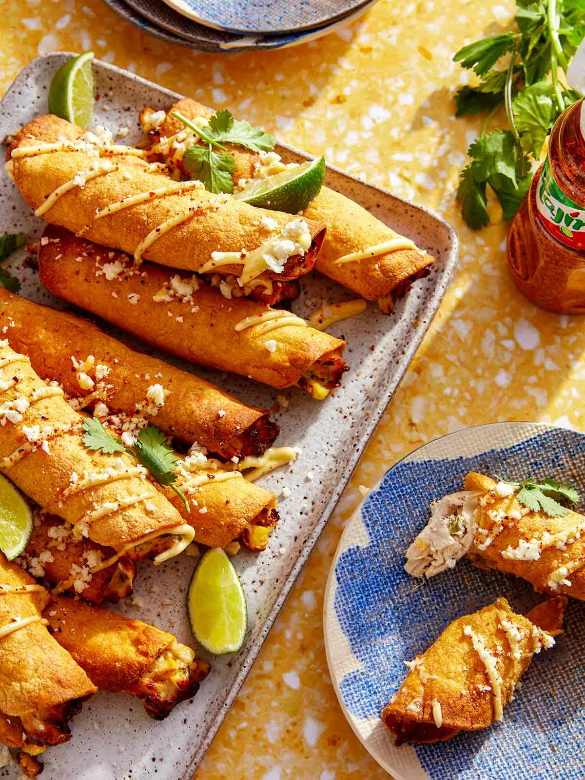 Taquitos on a platter with one being eaten on a plate.
