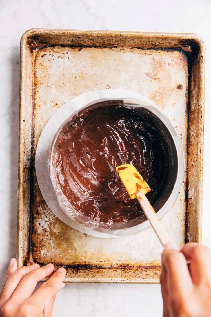 photo of the first layer of the milk bar cake being covered in the chocolate hazelnut ganache