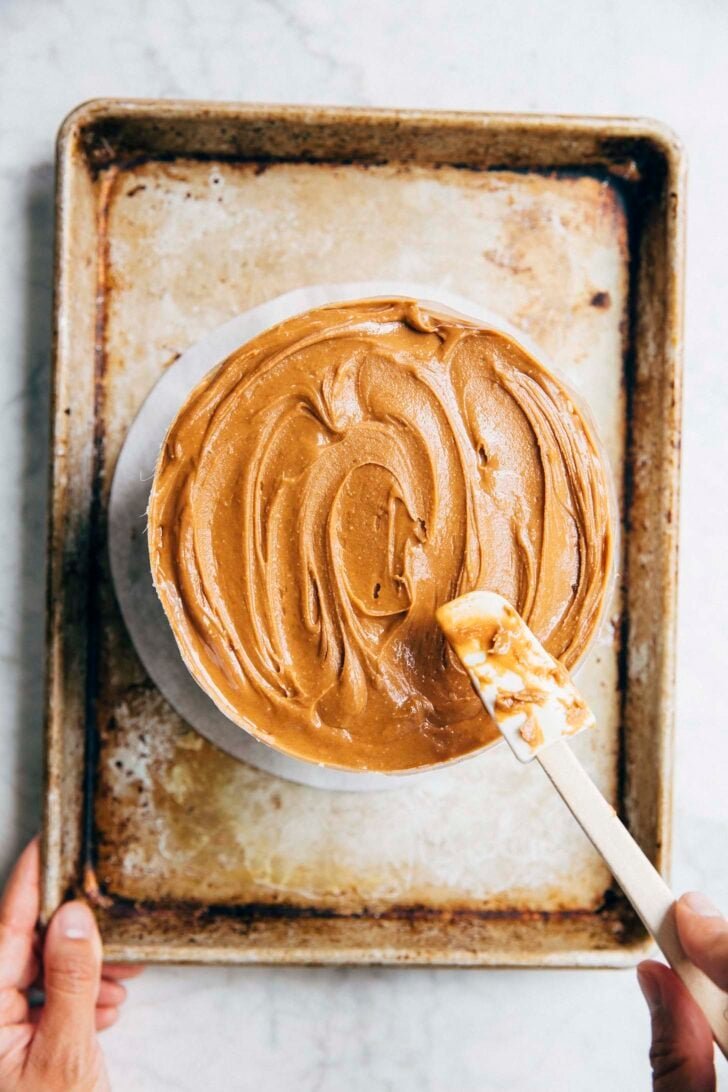 photo showing the milk bar banana layer cake being covered in the hazelnut frosting