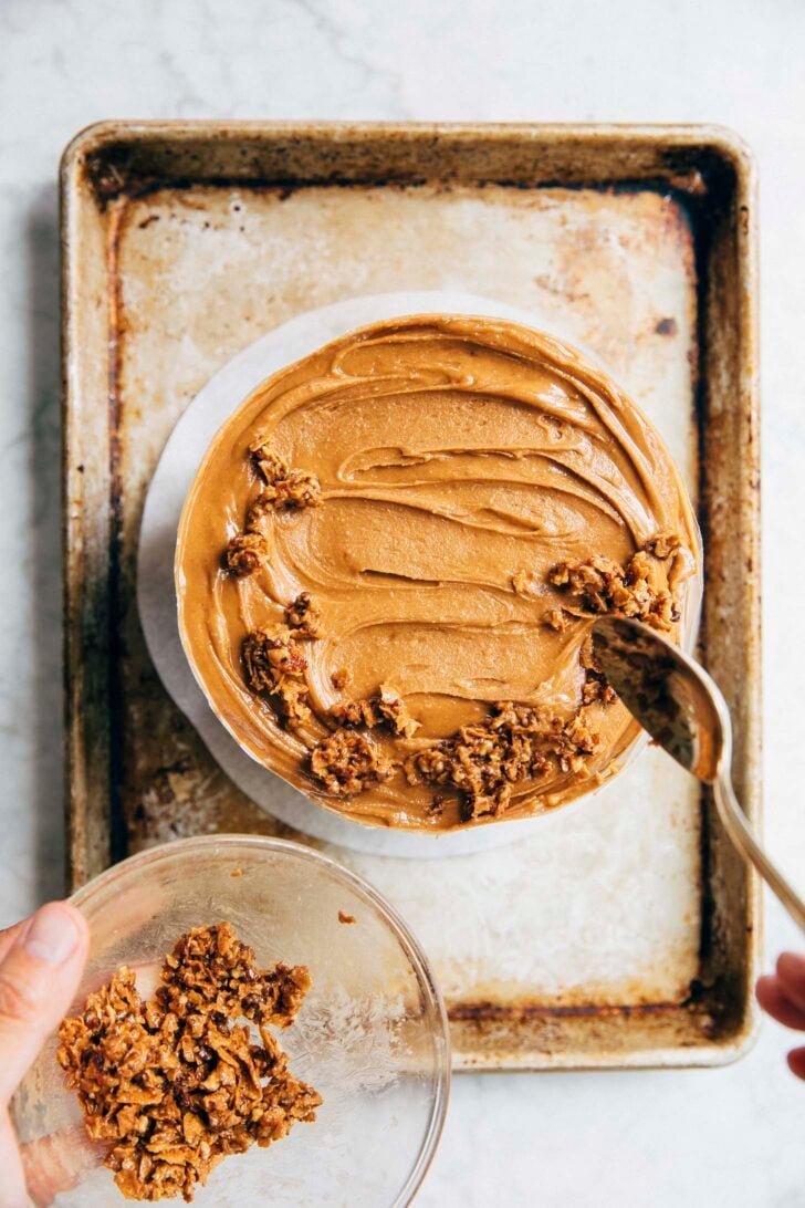 photo showing Michelle of Hummingbird High topping the hazelnut frosting with hazelnut crunch