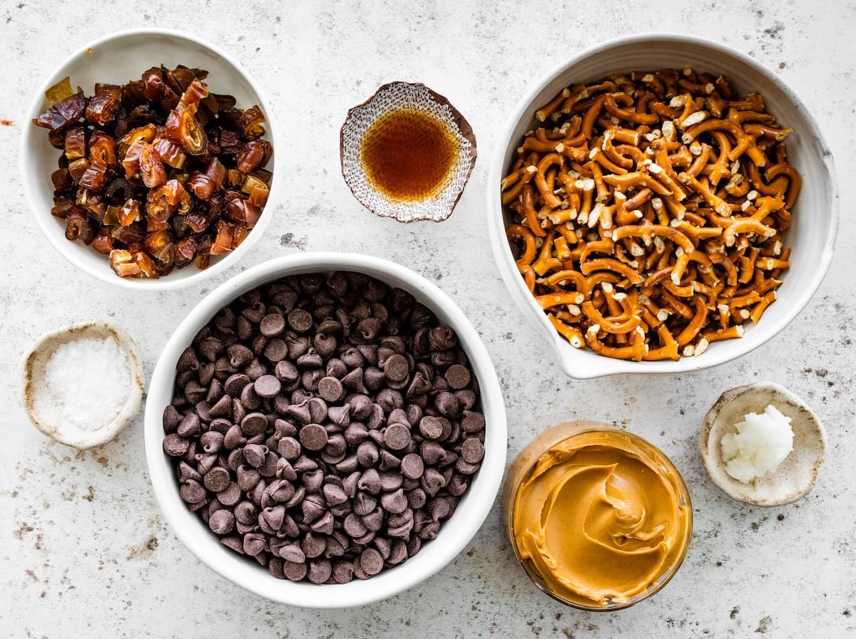 ingredients in bowls to make peanut butter pretzel clusters.