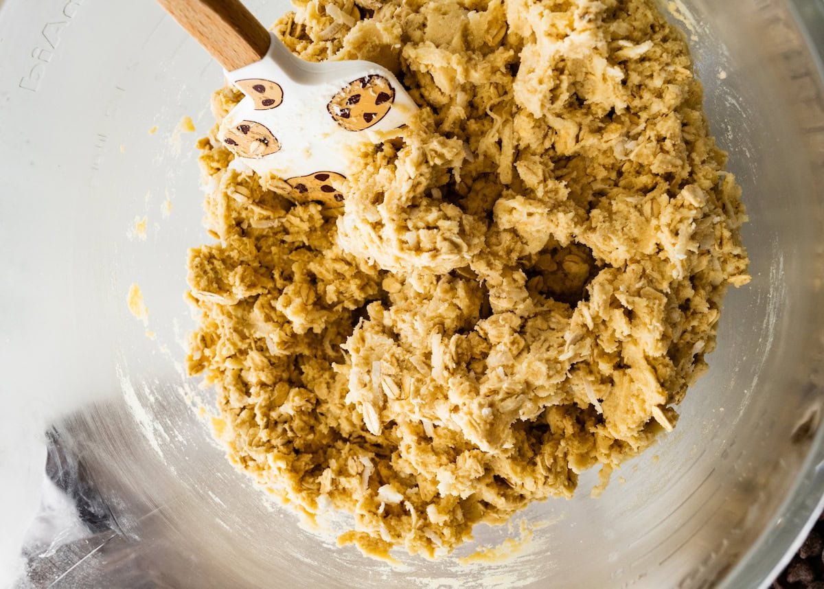 oatmeal coconut cookie dough in mixing bowl with spatula.