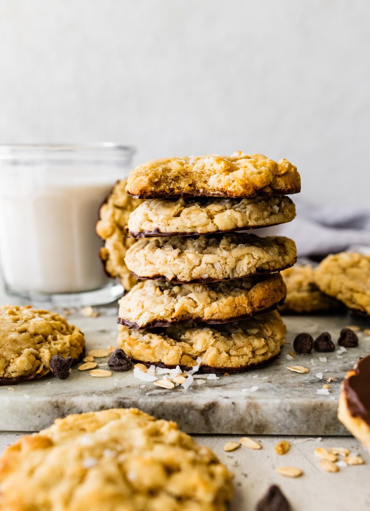 a stack of chocolate dipped coconut cookies with a glass of milk.