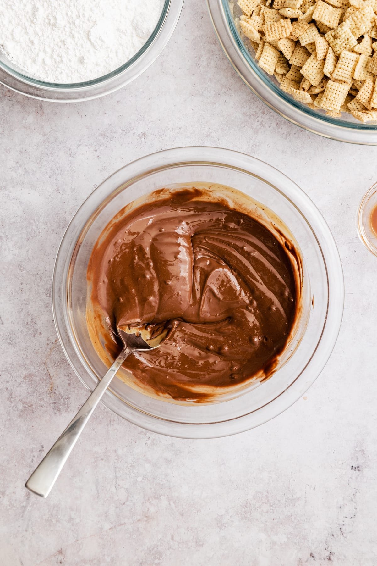 Homemade Puppy Chow is easy to make and SO addicting. This recipe for chocolate peanut butter-covered Chex cereal is a perfect party snack! Chocolate and peanut butter melted together in a glass mixing bowl.