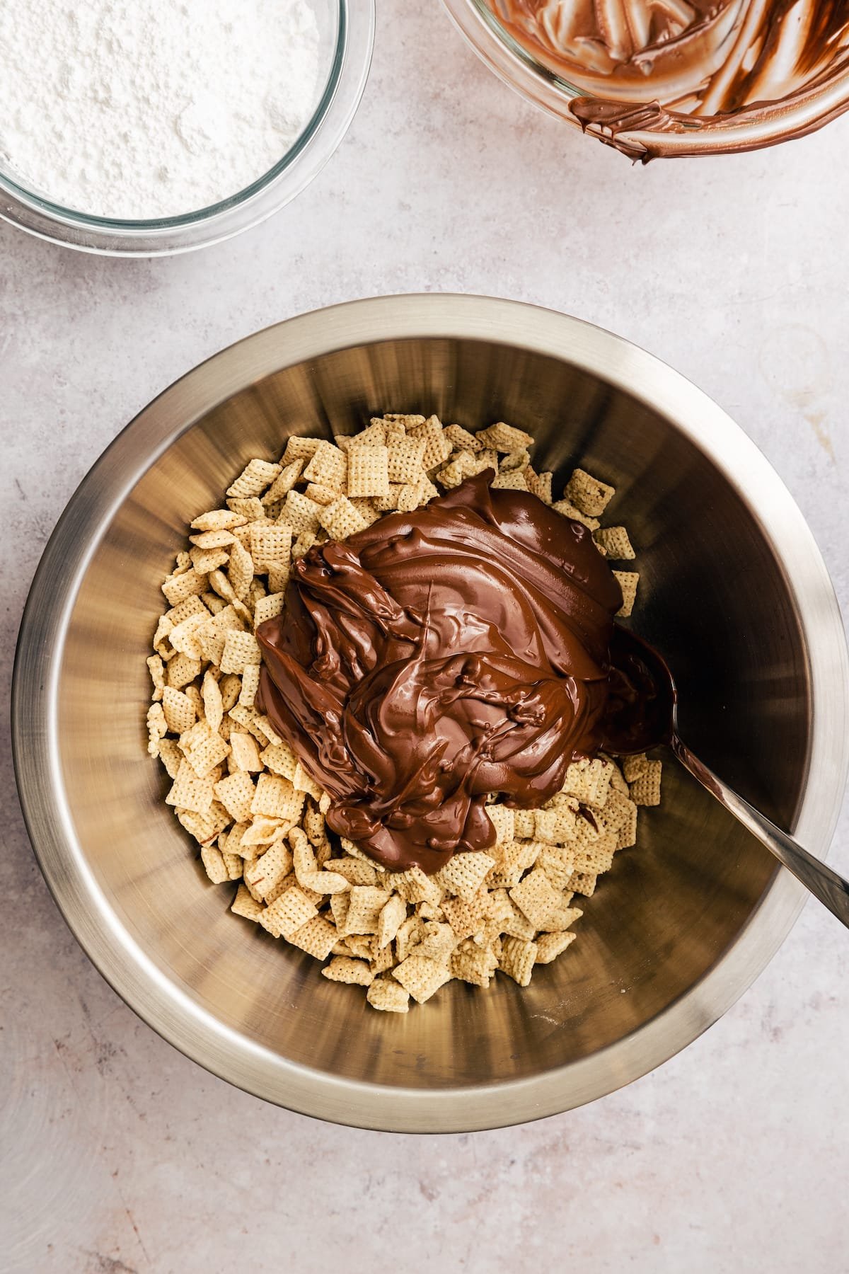Homemade Puppy Chow is easy to make and SO addicting. This recipe for chocolate peanut butter-covered Chex cereal is a perfect party snack! The chocolate peanut butter mixture is added into a large bowl with Chex cereal.