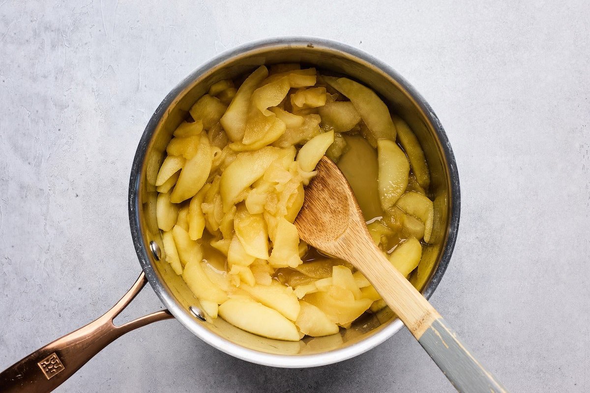 apple pie filling in pan with wooden spoon.