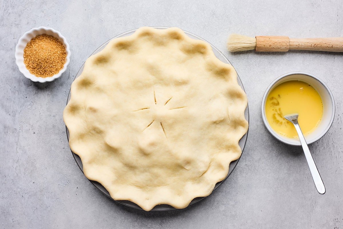 apple pie with pie dough crimped on top, ready for an egg wash.