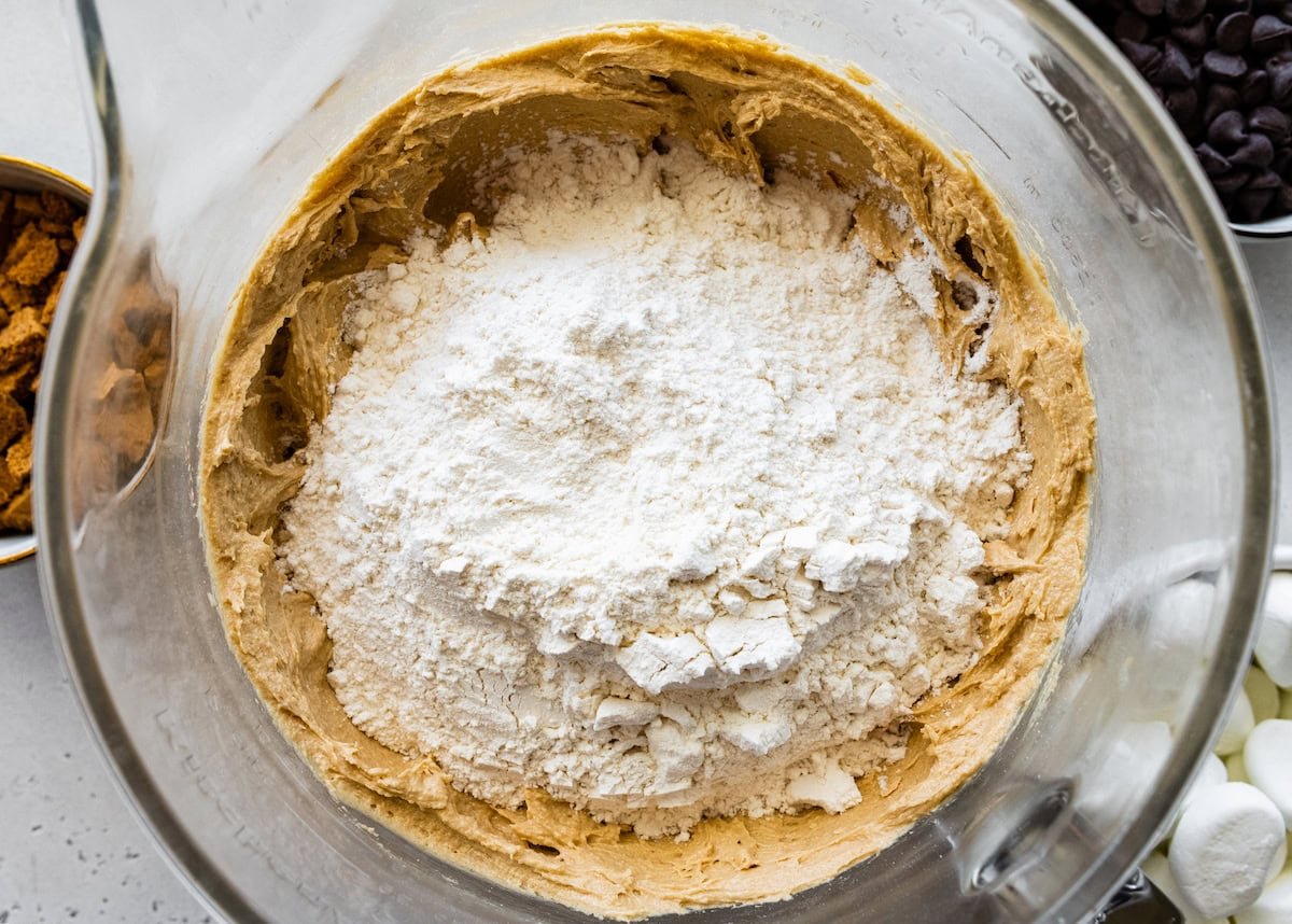 dry ingredients being added to the wet ingredients to make biscoff s'mores cookies. 
