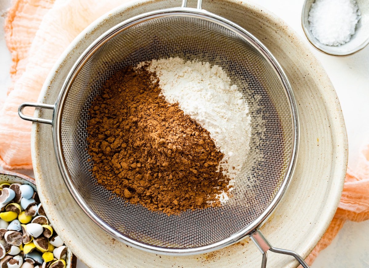 sifting cocoa powder and flour to make cadbury egg brownies. 