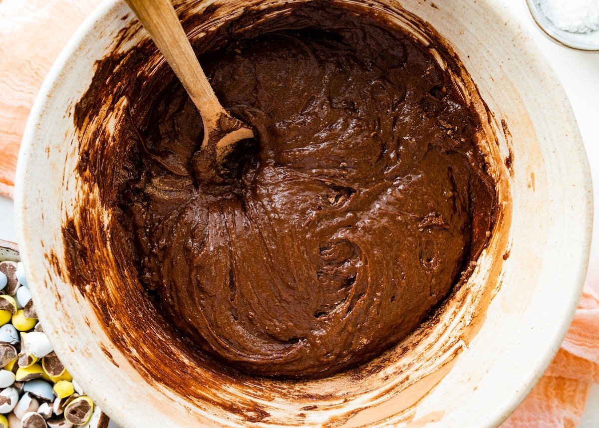 brownie batter in mixing bowl with wooden spoon. 