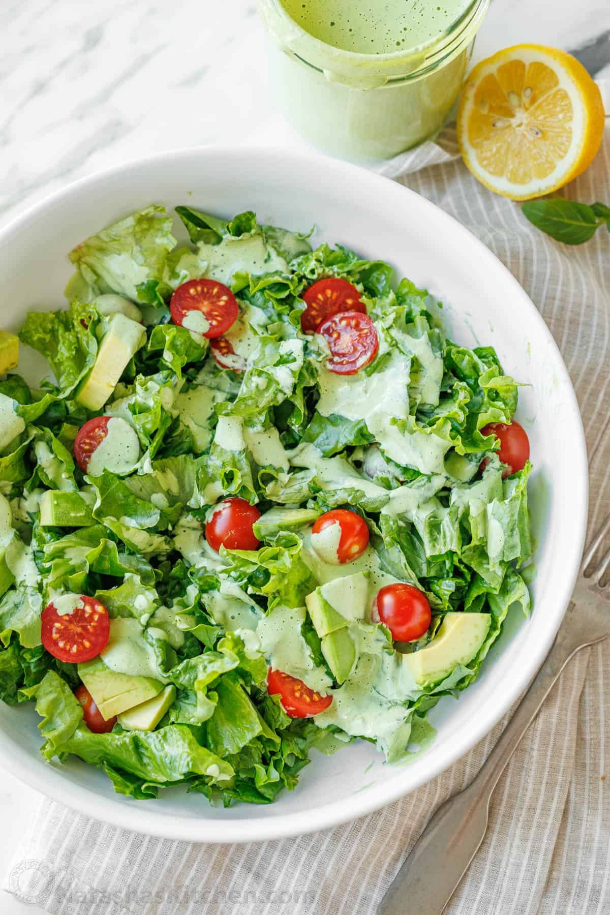 Fresh salad with tomatoes covered with Greek Goddess Dressing in a white bowl