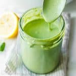 Homemade Green Goddess Dressing in a mason job and dripping from a spoon