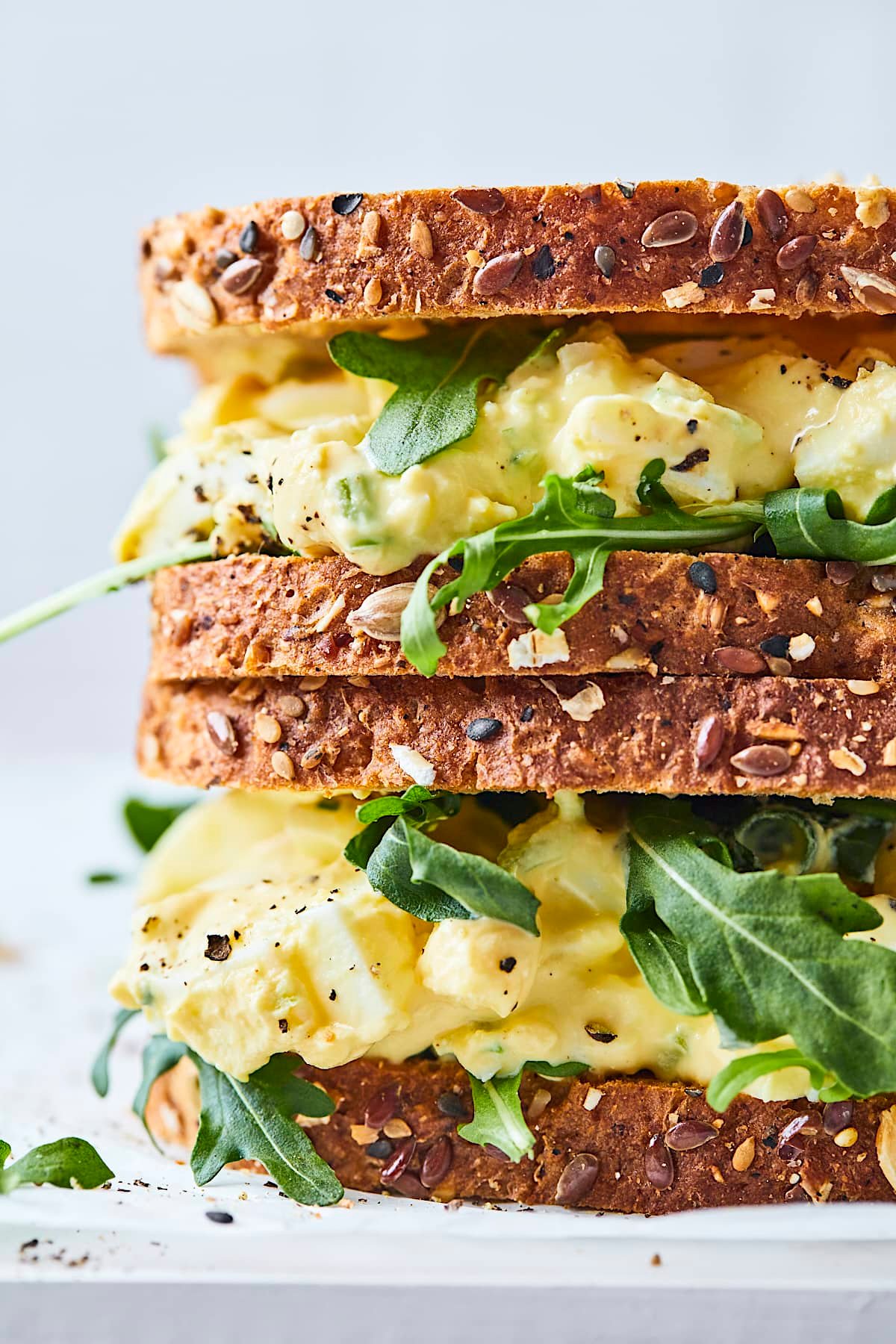 close up of 2 egg salad sandwiches stacked on top of each other. 