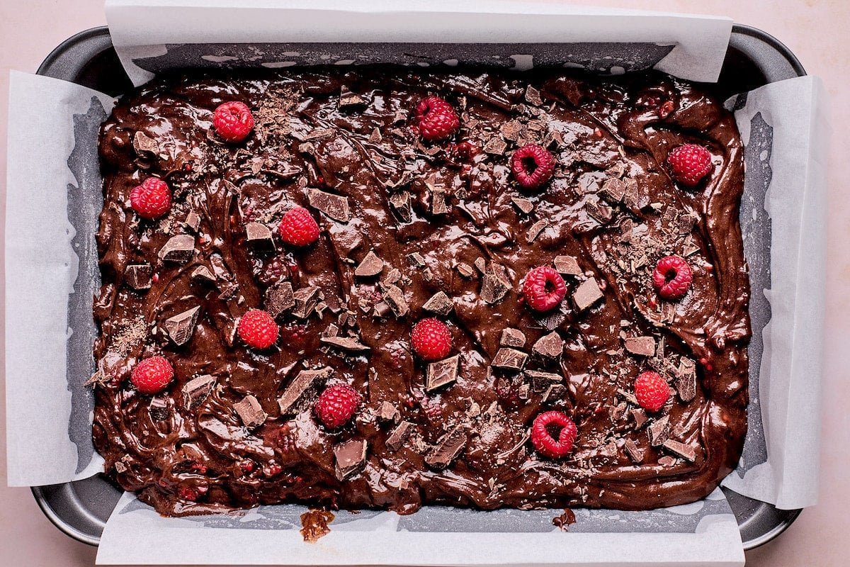 raspberry brownie batter in pan with parchment paper. 