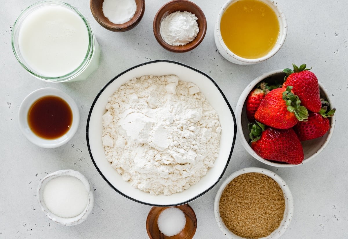 baking ingredients and fresh strawberries in bowls to make strawberry biscuits. 