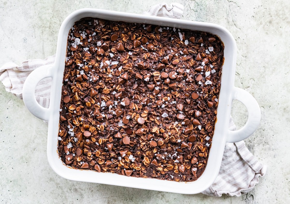 chocolate banana baked oatmeal mixture in baking pan topped with chocolate chips. 