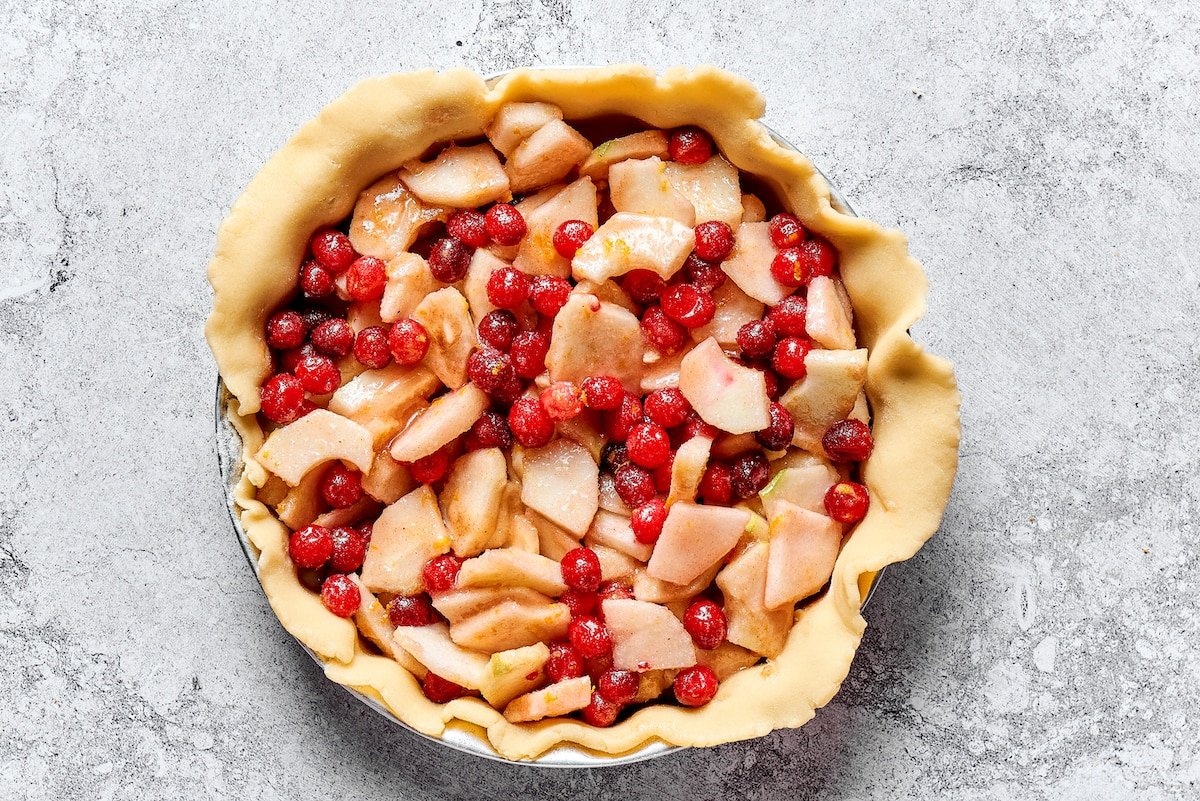pie dough in pie pan with apple cranberry filling.