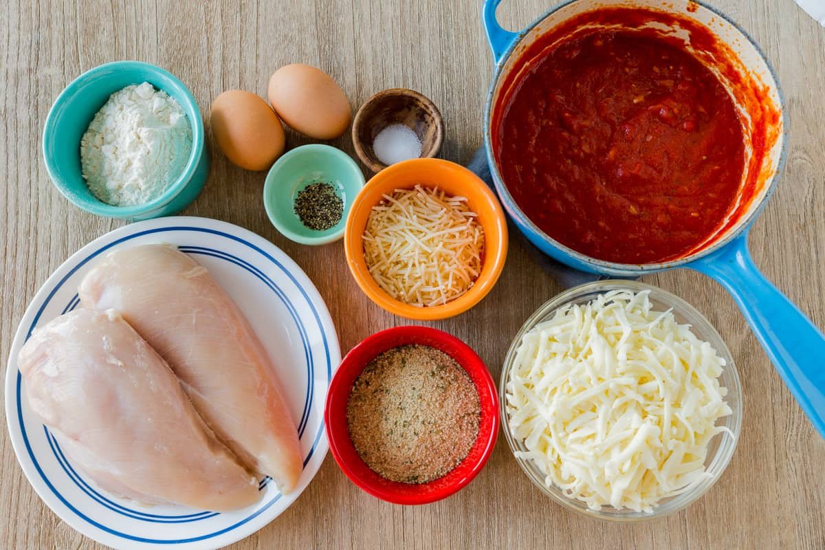 Classic Chicken Parmesan recipe with parmesan crusted tender chicken, topped with marinara and cheese. Chicken Parm is an easy, excellent 30 minute dinner. #chickenparmesan #chickenparmesanrecipe #parmesancrustedchicken #bakedchickenparmesan #easychickenparmesan #natashaskitchen Ingredients for chicken parmesan with homemade marinara sauce, chicken breast, cheese, bread crumbs, eggs, flour and seasonings