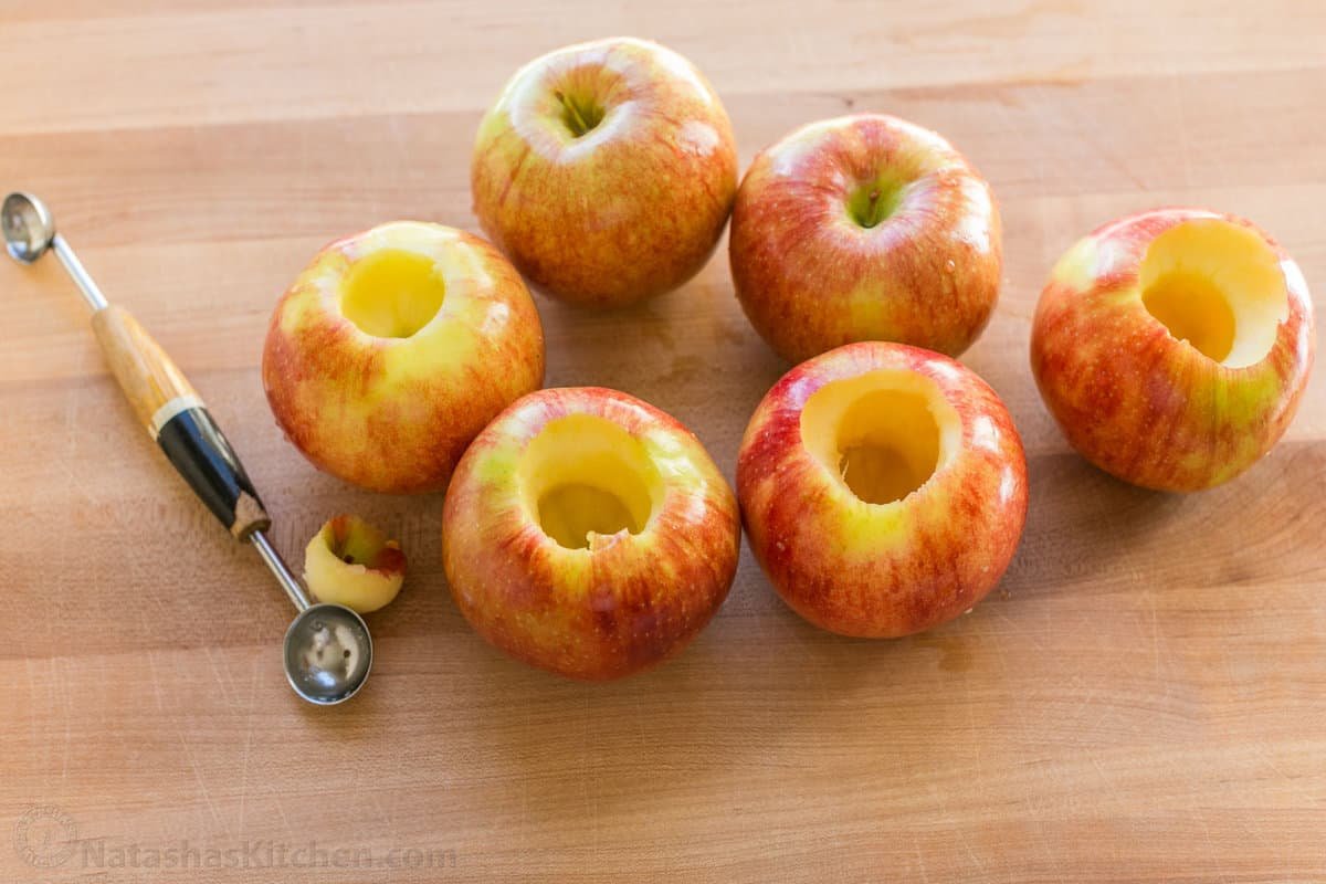 These cozy Baked Apples are infused with fall flavor inside and out. Stuffed with cinnamon sugar, they taste just like apple pie filling! Apples with the cores removed next to a melon baller.