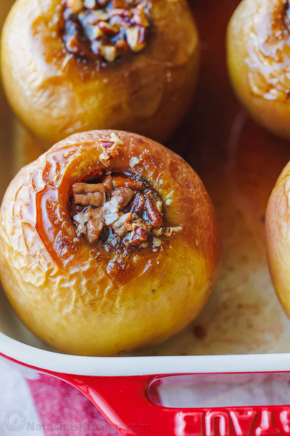 These cozy Baked Apples are infused with fall flavor inside and out. Stuffed with cinnamon sugar, they taste just like apple pie filling! Close up of baked apples filled with cinnamon sugar in a baking dish.