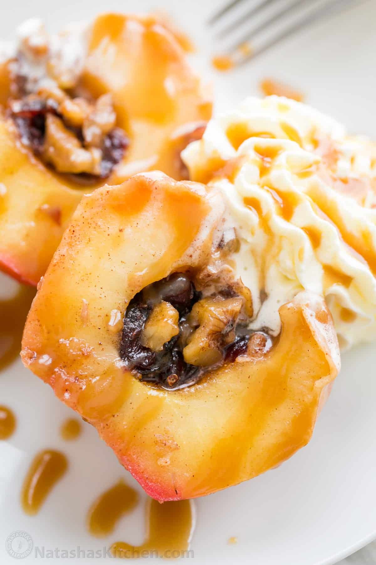 These cozy Baked Apples are infused with fall flavor inside and out. Stuffed with cinnamon sugar, they taste just like apple pie filling! A baked apple topped with whipped cream and caramel and sliced in half to reveal the cinnamon sugar filling.