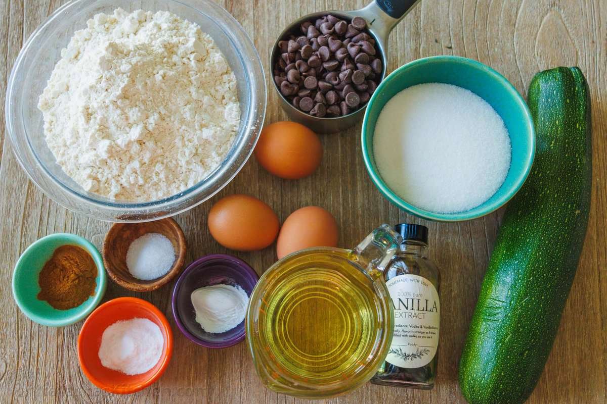 Ingredients to make zucchini muffins flour, zucchini, eggs, sugar, oil, vanilla, chocolate chips