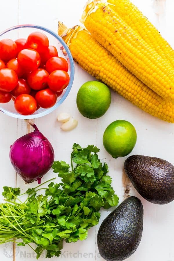 Ingredients for summer corn salad with avocado, tomatoes, cilantro, red onion, garlic and lime juice