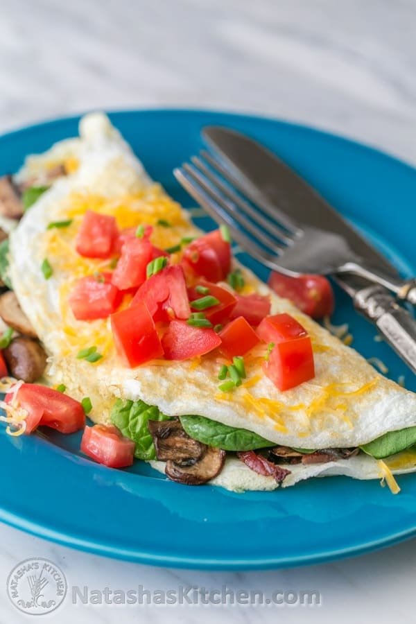 This fluffy egg white omelette is loaded with bacon, mushrooms, cheese, and fresh spinach which softens perfectly inside the omelette. So satisfying! | NatashasKitchen.com 