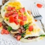 This fluffy egg white omelette is loaded with bacon, mushrooms, cheese, and fresh spinach which softens perfectly inside the omelette. So satisfying! | NatashasKitchen.com