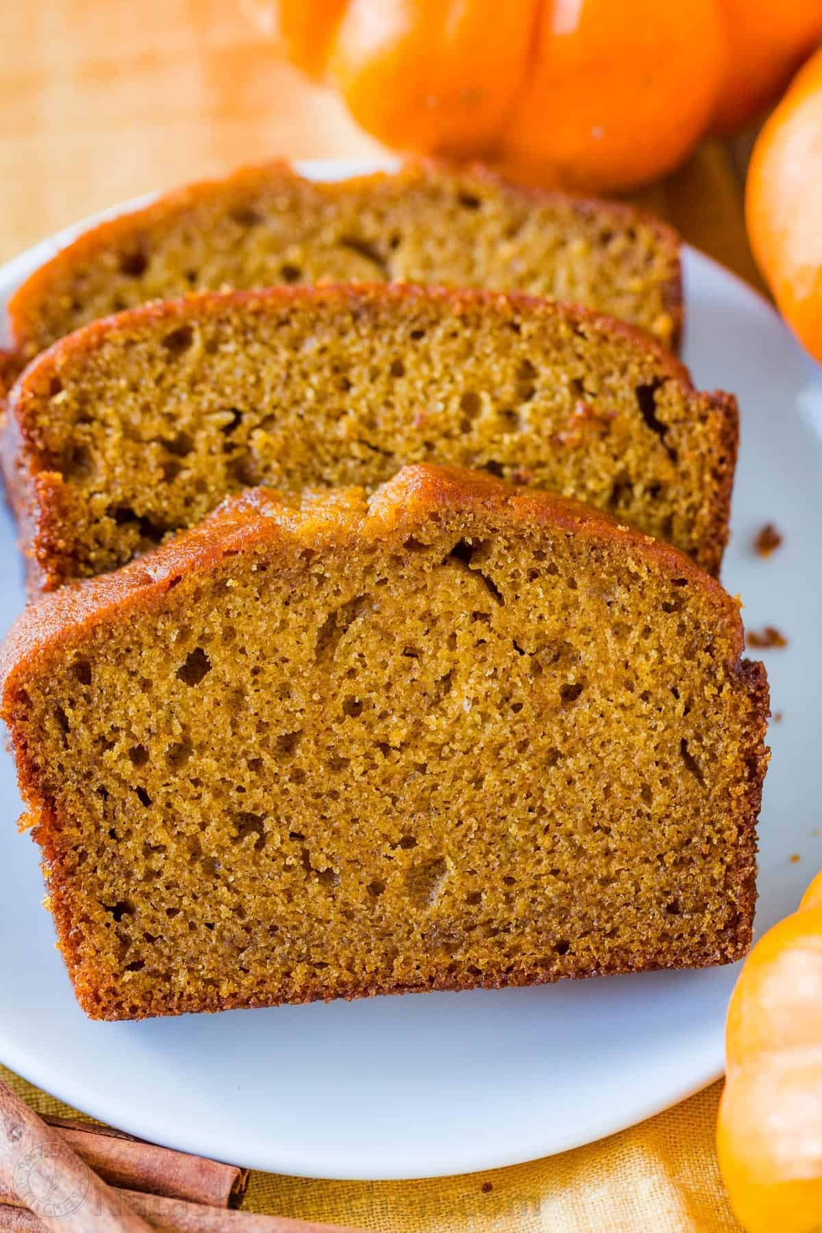 Pumpkin Bread has a soft and moist crumb with wonderful pumpkin flavor. This is our go-to easy pumpkin bread recipe and it's freezer friendly! #pumpkinbread #pumpkinbreadrecipe #easypumpkinbread #pumpkin #pumpkinrecipes #thanksgiving #dessert #bread Classic sliced moist pumpkin bread on a plate