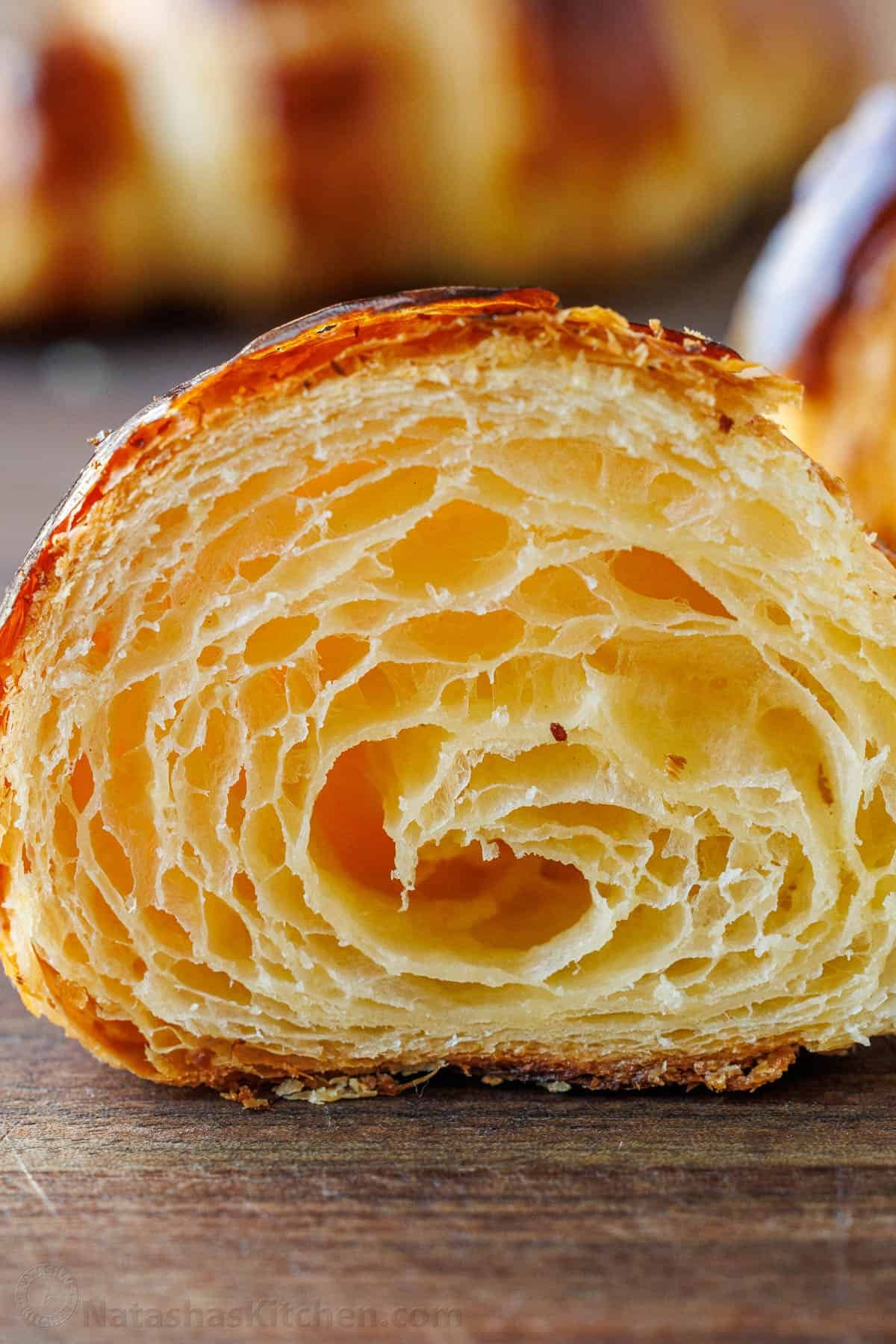 Learn how to make Croissants (with tips from a French Chef!). These rise beautifully, are crisp on the outside, and have soft, flaky layers. up close center cut of croissant showing layers