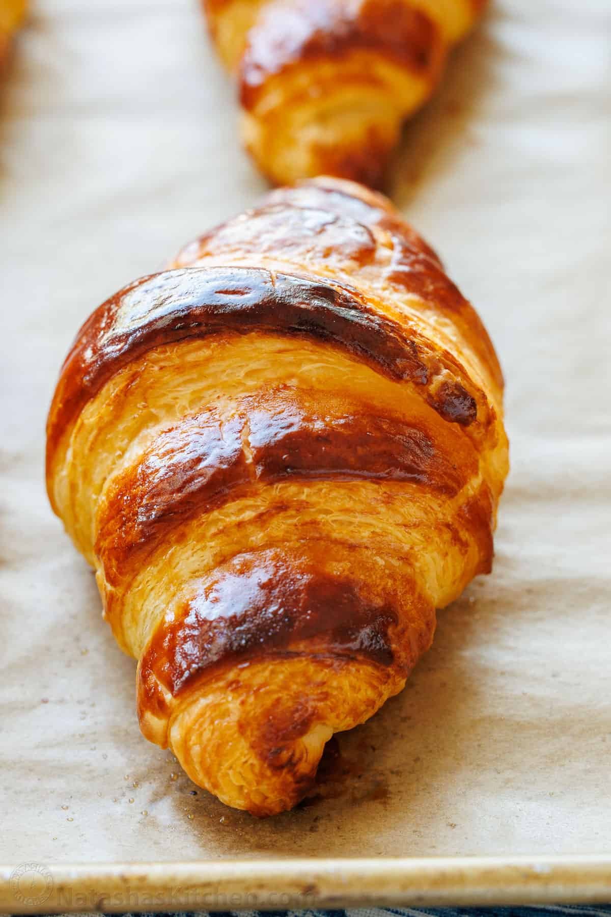 Freshly baked French croissant—crispy on the outside and soft on the inside. With tips from Paris, I've perfected this recipe and know you will love it! Up close exterior of a baked homemade croissant