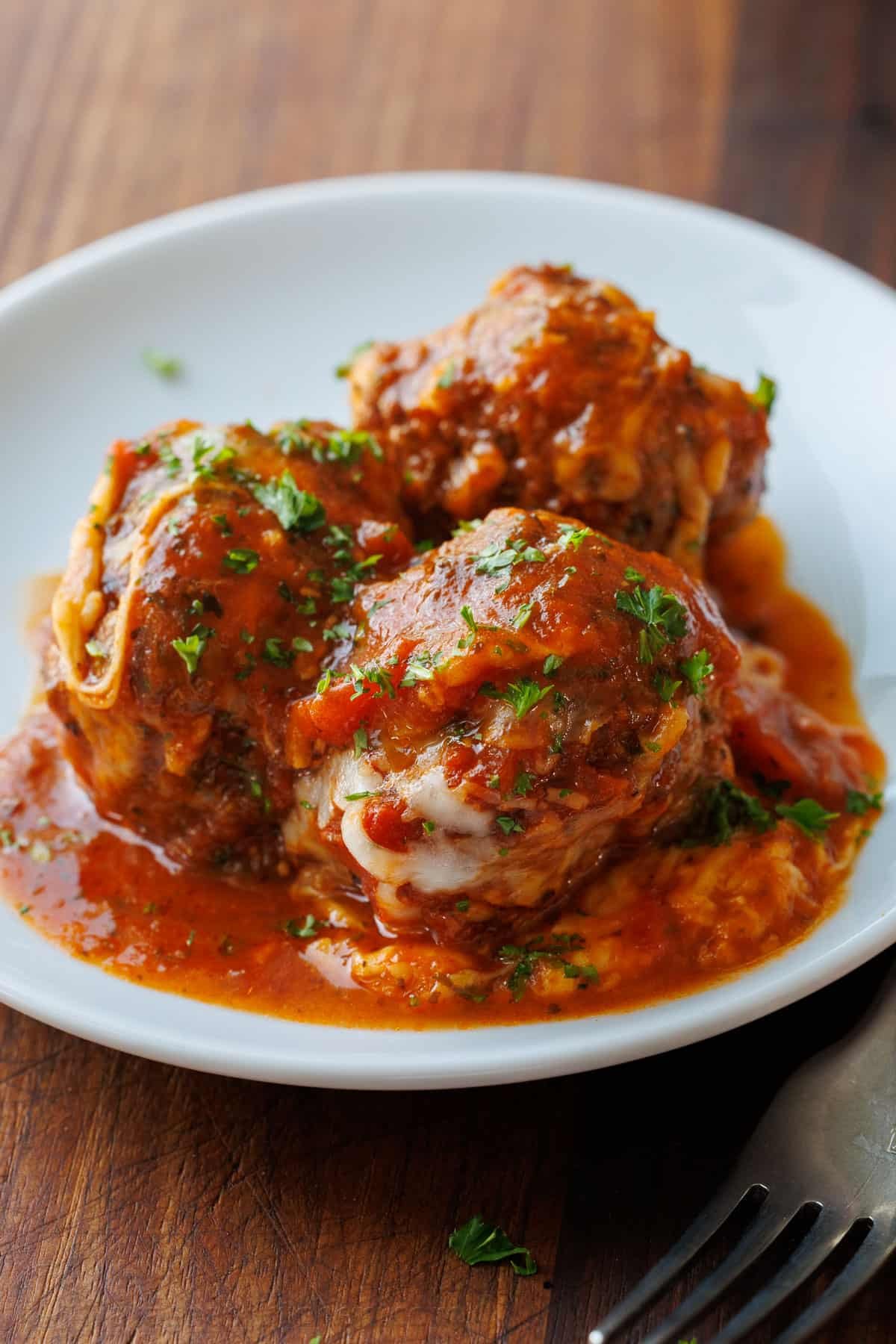 Meatballs Parmesan combines the best Italian dishes into one easy casserole. Homemade saucy Parmesan Meatballs topped with gooey cheese. 3 homemade meatballs parmesan on a plat with marinara sauce
