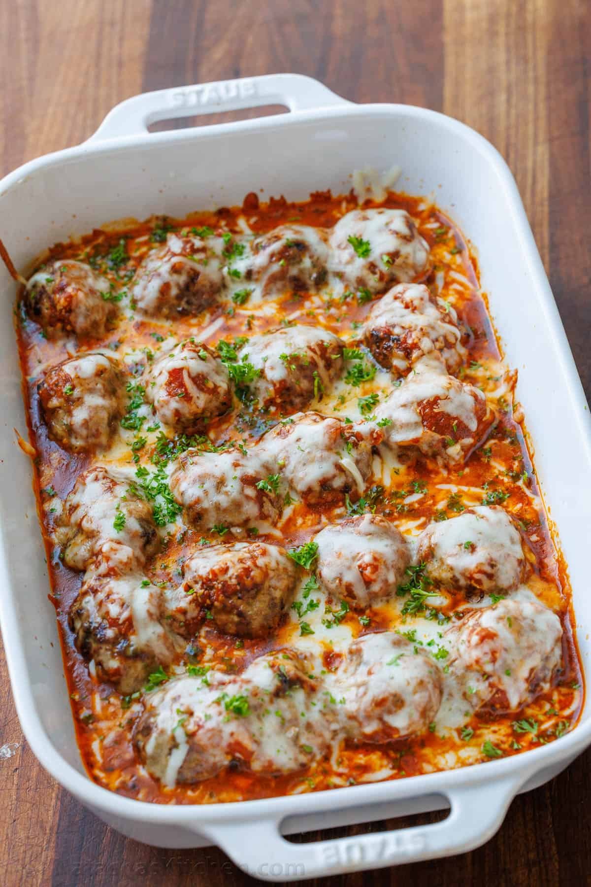 Meatballs Parmesan combines the best Italian dishes into one easy casserole. Homemade saucy Parmesan Meatballs topped with gooey cheese. Casserole Dish with Make-ahead Meatballs Parmesan Casserole on a wooden table