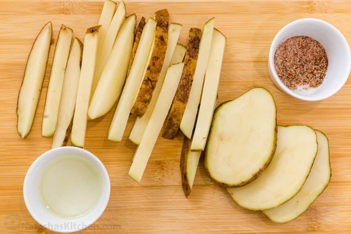 Homemade Air Fryer French Fries are so easy to make and taste much better than frozen fries! The Air Fryer makes it quick and easy to serve. Sliced spuds on a cutting board with seasoning and oil
