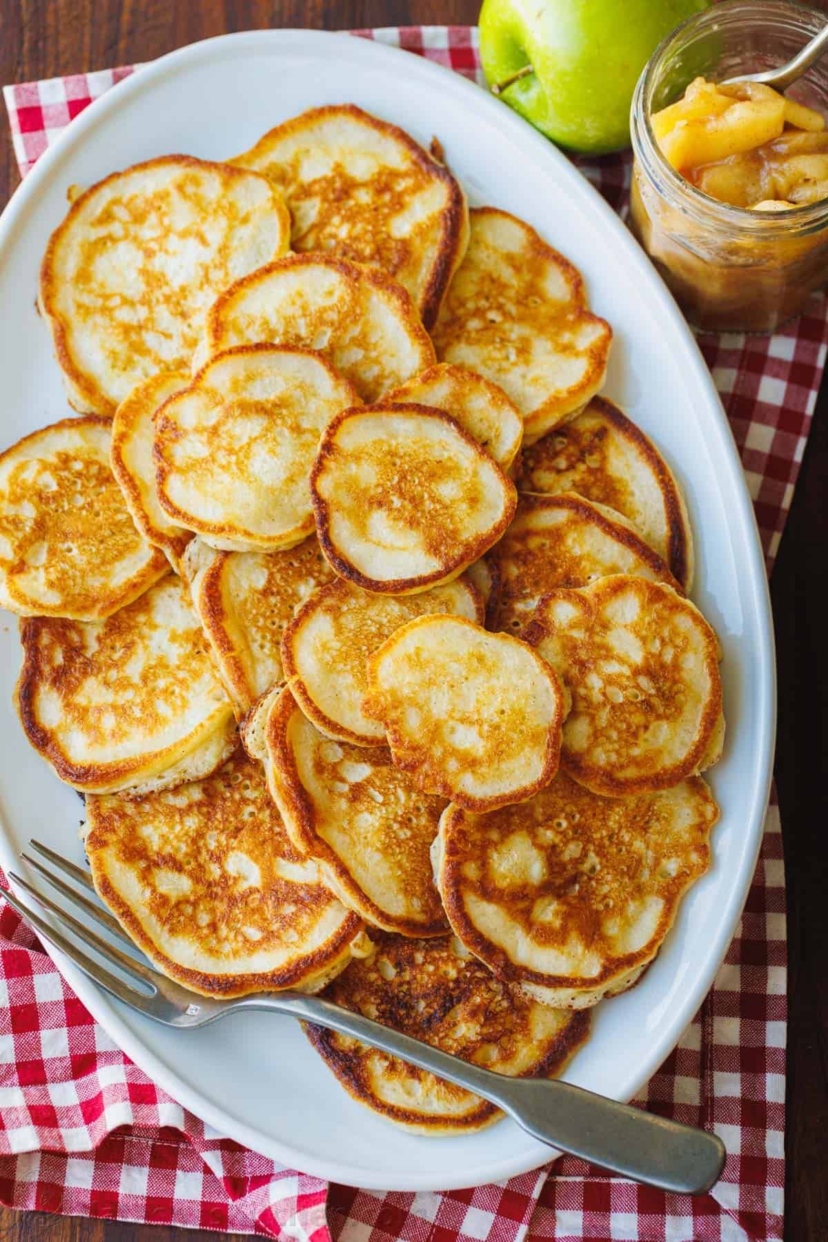 A large oval platter full of spiced apple pancakes.
