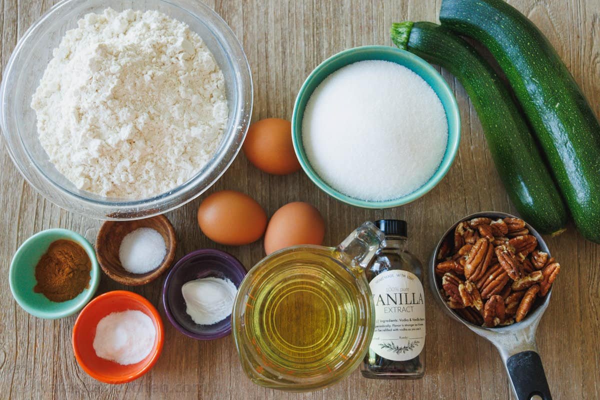Ingredients to make zucchini bread, flour, sugar, eggs, vanilla, cinnamon, pecans