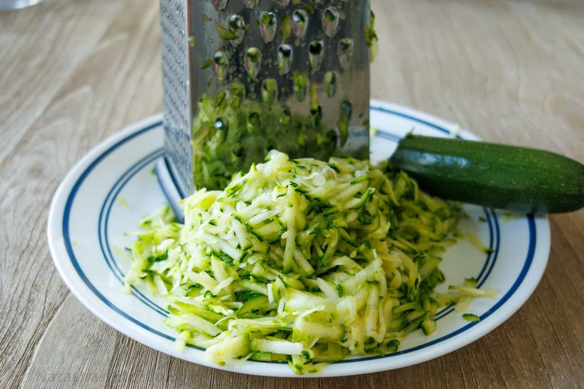 Grated zucchini on a plate with a box grater