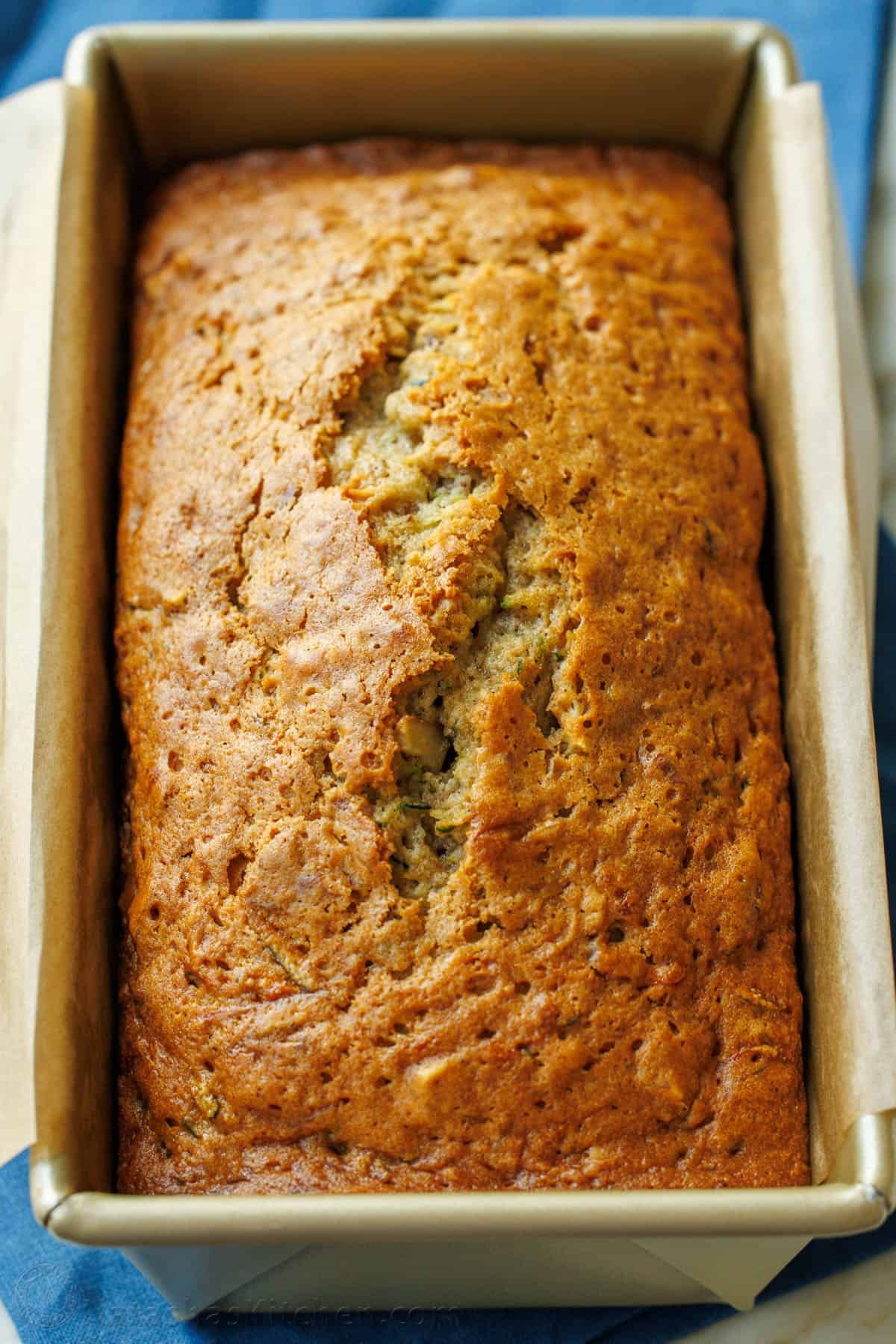 Loaf of zucchini bread in loaf pan with parchment paper