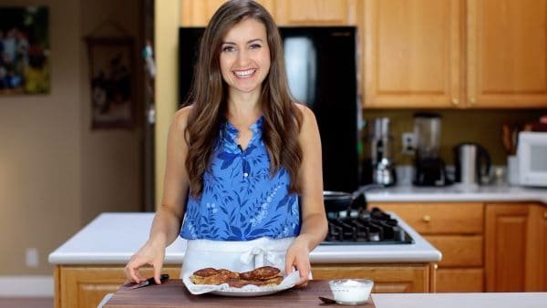 Natasha standing in her kitchen with stuffed potato pancakes in front of her 