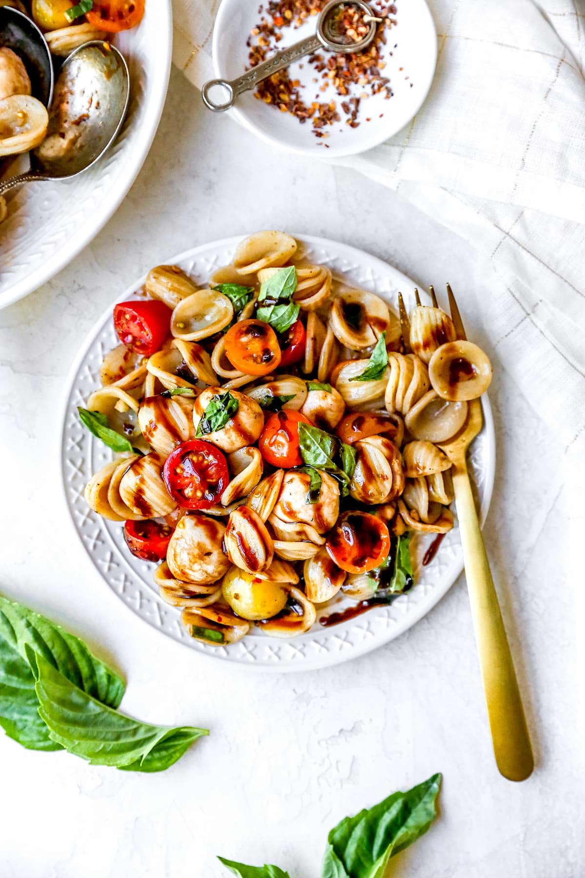 caprese pasta salad in bowl with balsamic glaze. 
