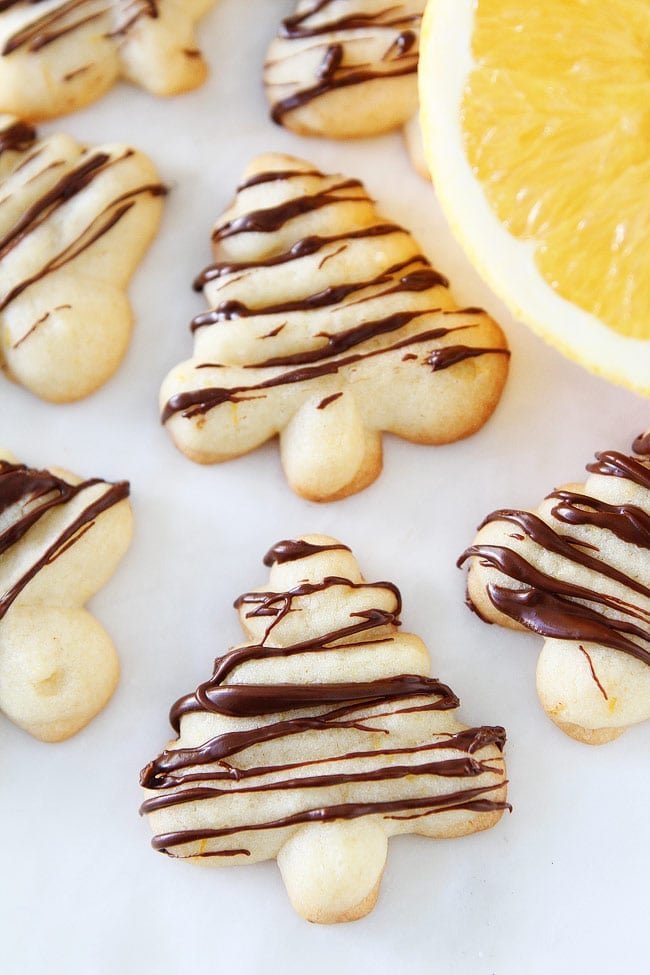 Orange Chocolate Spritz Cookie Recipe on twopeasandtheirpod.com Buttery spritz cookies with a hint of orange and a drizzle of chocolate. These festive cookies are perfect for the holiday season. Orange Chocolate Spritz Cookie Recipe