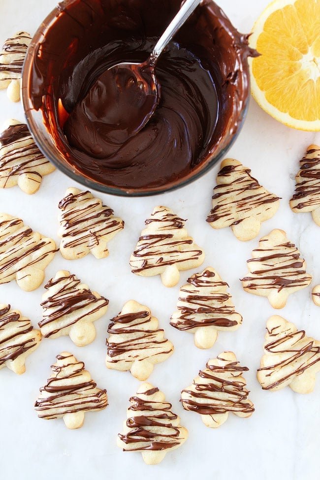 Orange Chocolate Spritz Cookie Recipe on twopeasandtheirpod.com Buttery spritz cookies with a hint of orange and a drizzle of chocolate. These festive cookies are perfect for the holiday season. Orange Chocolate Spritz Cookie Recipe